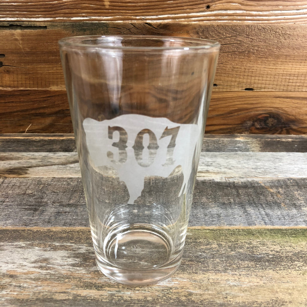 307 Bison Pint Glass Enjoy your favorite beverage in our 16oz capacity pint glass with the '307' designed right into the Wyoming Bison.  Be a part of the herd with a 307 Bison Pint Glass from WyoMade.  Capacity 16 oz    WyoMade is a Wyoming Craft Apparel brand located in the heart of Downtown Casper, Wyoming. 